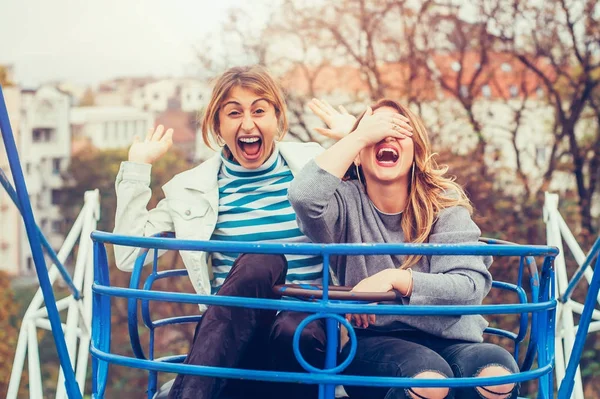 Két vidám lány szórakozás merry go round — Stock Fotó