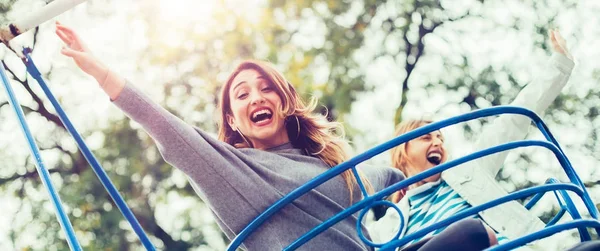 Dos chicas alegres disfrutando de su paseo en el parque de atracciones —  Fotos de Stock