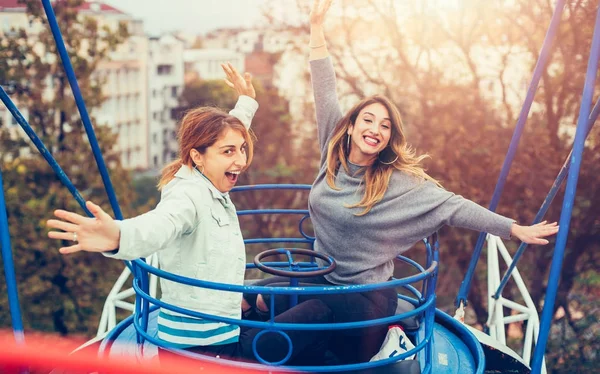 Két vidám lány szórakozás merry go round — Stock Fotó