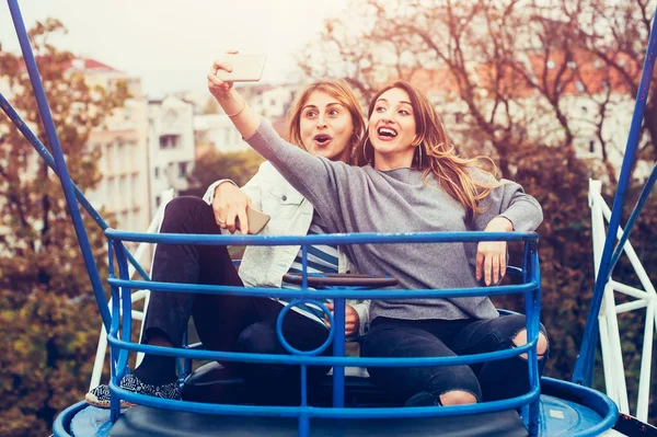 Dos chicas tomando selfie mientras se divierten en el parque de atracciones — Foto de Stock