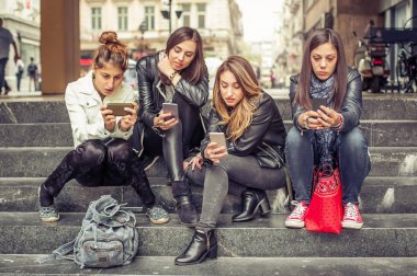 Smartphone ile şehir merdivenlerde oturan kız grubu