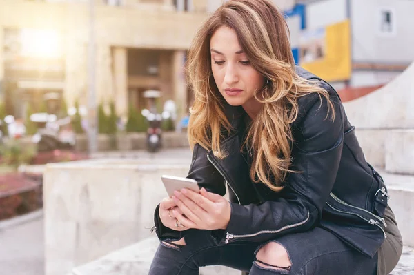 Frau sitzt auf der Straße, tippt Nachricht, chattet auf Smartphone — Stockfoto