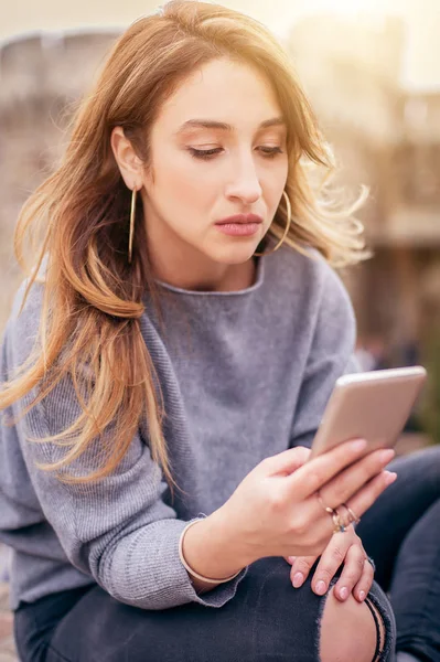 Frau sitzt auf der Straße, tippt Nachricht, chattet auf Smartphone — Stockfoto