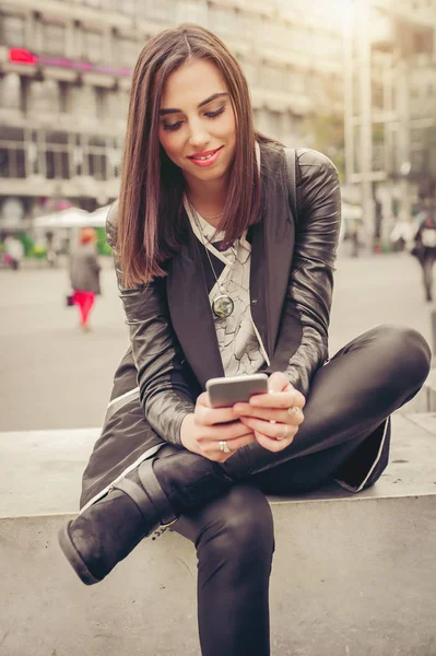 Glückliche Frau sitzt auf der Straße, tippt Nachricht, chattet auf Smart — Stockfoto