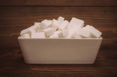 Ahşap arka plan üzerinde seramik kase küp beyaz şeker