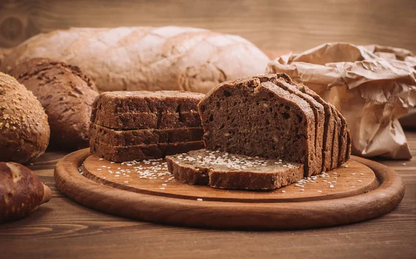 Foto de muchos panes horneados mixtos en mesa de madera rústica — Foto de Stock