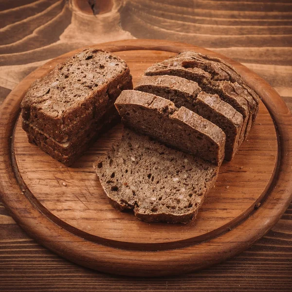 Pieczone różne chleby i bułki rustykalne drewniane tabela — Zdjęcie stockowe