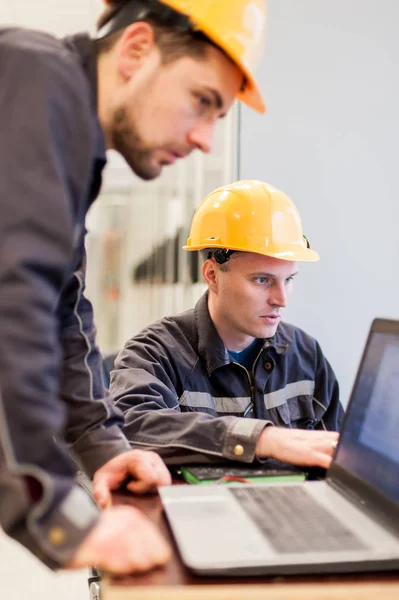 Field service crew engineers inspect relay protection system with laptop computer. Bay control unit. Medium voltage switchgear