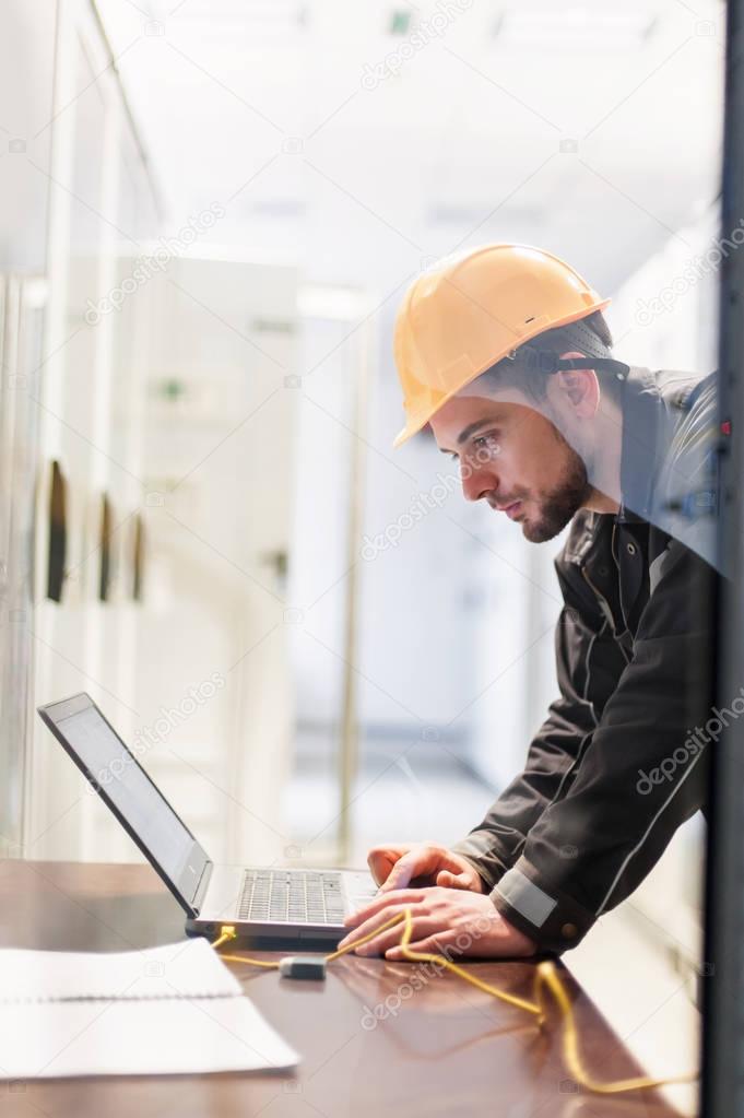 Maintenance engineer inspect relay protection system with laptop computer. Bay control unit. Medium voltage switchgear