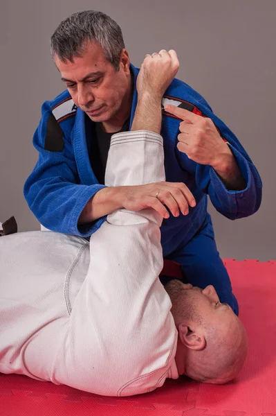 Instructor de jiu jitsu brasileño demuestra brazo de combate terrestre — Foto de Stock