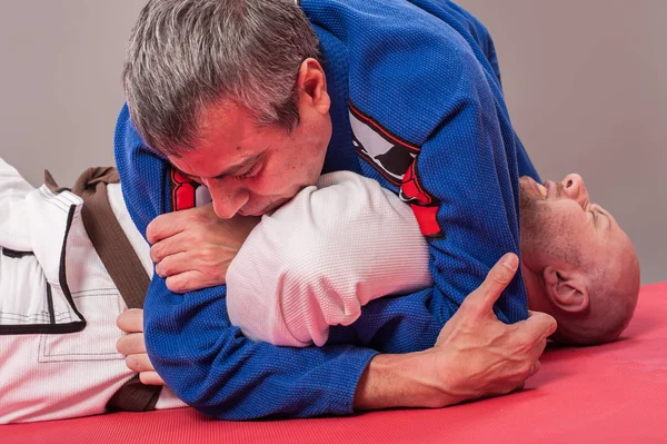 Instructor de jiu jitsu brasileño demuestra brazo de combate terrestre — Foto de Stock