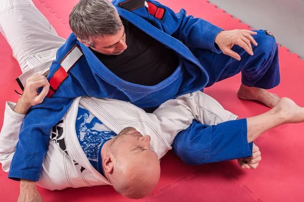 Instrutor brasileiro de jiu jitsu demonstra braço de combate no solo — Fotografia de Stock