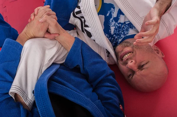 Instrutor brasileiro de jiu jitsu demonstra braço de combate no solo — Fotografia de Stock