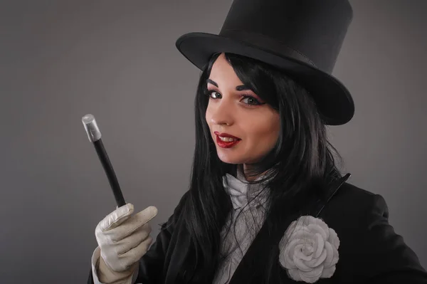 Female magician in costume suit with magic stick doing trick - Stock ...