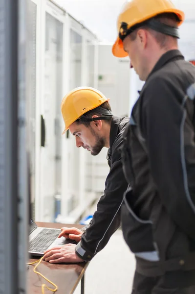 Field service engineers inspect relay protection system with lap