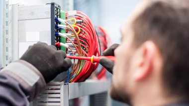 Closeup of electrician engineer works with electric cable wires clipart