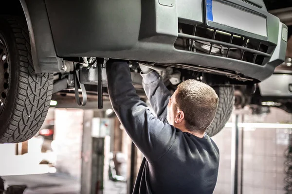 Otomatik tamirci aracın altındaki durumu kontrol ediyor. — Stok fotoğraf