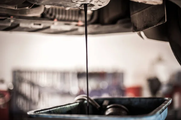 Mechaniker entleert Motoröl aus Tank unter dem Auto — Stockfoto