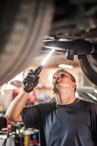 Reparador mecánico de automóviles que comprueba la condición bajo coche en el vehículo l —  Fotos de Stock