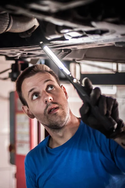 Reparador mecánico de automóviles que comprueba la condición bajo coche en el vehículo l —  Fotos de Stock