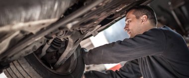 Tamirci, frenlerin ve tekerleklerin durumunu kontrol ediyor.