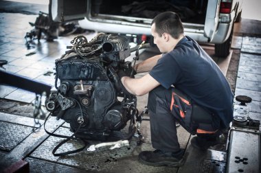 Arabadan çıkarılmış motor. Otomatik tamirci araba motorunu tamir eder
