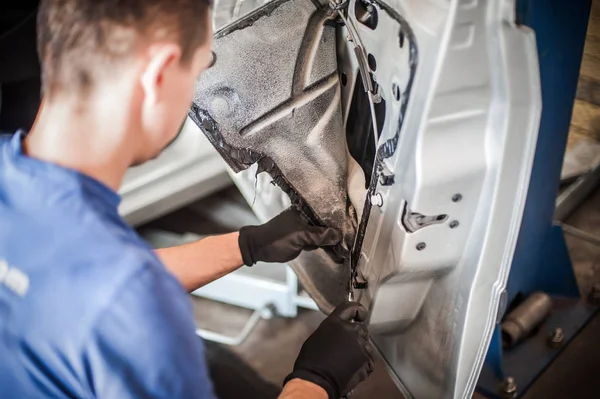 Car mechanic works on the interior of a car door