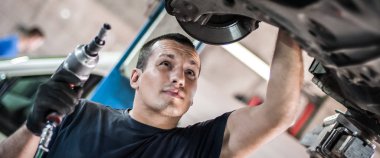 Otomatik tamirci aracın altındaki durumu kontrol ediyor.