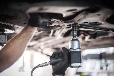 Otomatik tamirci aracın altındaki durumu kontrol ediyor.