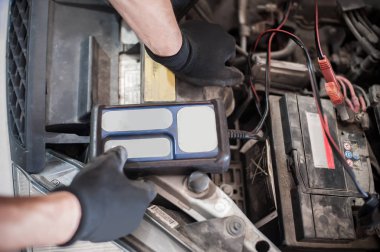Araba tamircisi ba ile otomotiv akümülatörünü kontrol ve test ediyor