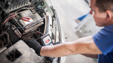 Araba tamircisi ba ile otomotiv akümülatörünü kontrol ve test ediyor