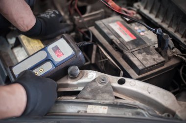 Araba tamircisi ba ile otomotiv akümülatörünü kontrol ve test ediyor