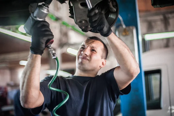 Otomatik tamirci aracın altındaki durumu kontrol ediyor. — Stok fotoğraf