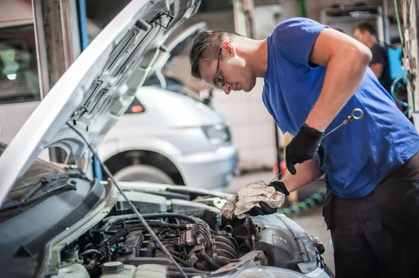 Reparador mecánico automático que comprueba el nivel de aceite en el motor del coche —  Fotos de Stock