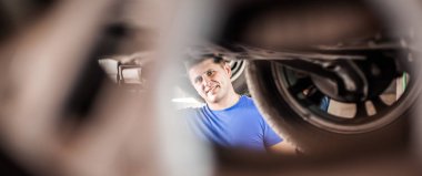 Otomatik tamirci aracın altındaki durumu kontrol ediyor.