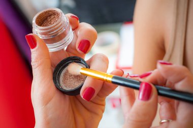 Makyaj sanatçısı kadın modeline göz farı uyguluyor.