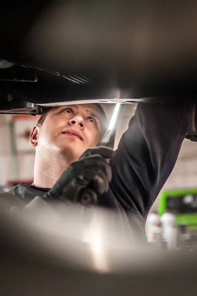 Reparador mecánico de automóviles que comprueba la condición bajo coche en el vehículo l —  Fotos de Stock