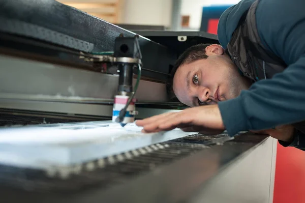 Electrical engineer repairs a laser cutting head on large CNC computer numerical control printing and cutting machine