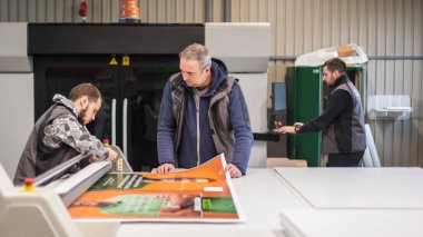 Geniş bir grup işçi matbaa teknisyeni dijital matbaa ve matbaa ofisinde çalışıyor.