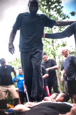Sivillerden oluşan büyük bir grup yerde yatan kalabalığı ezip geçiyor. Askeri dayanıklılık eğitim kampında, doğada, dışarıda.