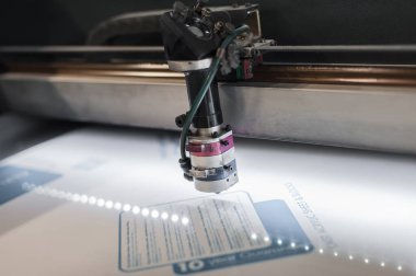 Elektrik mühendisi büyük CNC bilgisayar sayısal kontrol yazdırma ve kesme makinesinin lazer kesme başını onardı