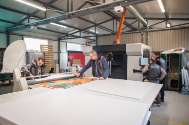 Geniş bir grup işçi matbaa teknisyeni dijital matbaa ve matbaa ofisinde çalışıyor.