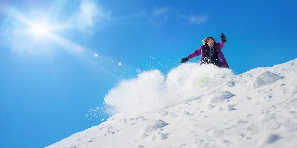 Very fast professional freerider snowboarder rolls and rides snowboard board and make big splash of snow. French Alps, Les 2 Alpes