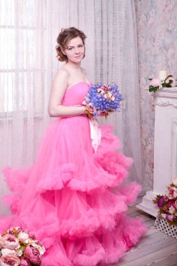 Kadın pembe arka planda düşünmenin ihlaline doğru bakıyor. Elbiseli güzel bir kadın portresi. Mutlu bir gülümseme. Oldukça karışık ırk Kafkasyalı esmer model..