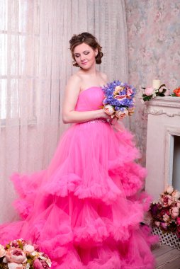 Kadın pembe arka planda düşünmenin ihlaline doğru bakıyor. Elbiseli güzel bir kadın portresi. Mutlu bir gülümseme. Oldukça karışık ırk Kafkasyalı esmer model..