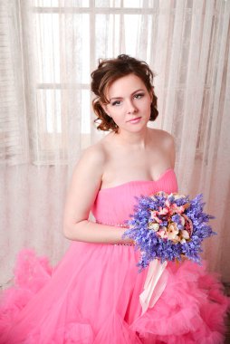 Kadın pembe arka planda düşünmenin ihlaline doğru bakıyor. Elbiseli güzel bir kadın portresi. Mutlu bir gülümseme. Oldukça karışık ırk Kafkasyalı esmer model..