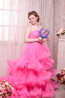 Kadın pembe arka planda düşünmenin ihlaline doğru bakıyor. Elbiseli güzel bir kadın portresi. Mutlu bir gülümseme. Oldukça karışık ırk Kafkasyalı esmer model.