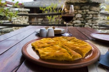 Tahta bir masada bir bardak şarap ve sıcak placinta..