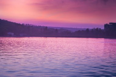 Güneşin günbatımında göldeki suyun kırmızı yansıması..