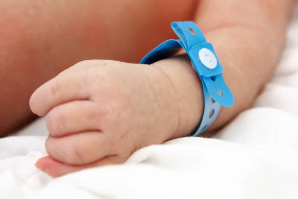 Asa de un bebé recién nacido con etiqueta azul. Hospital de maternidad, centro perinatal, maternidad — Foto de Stock